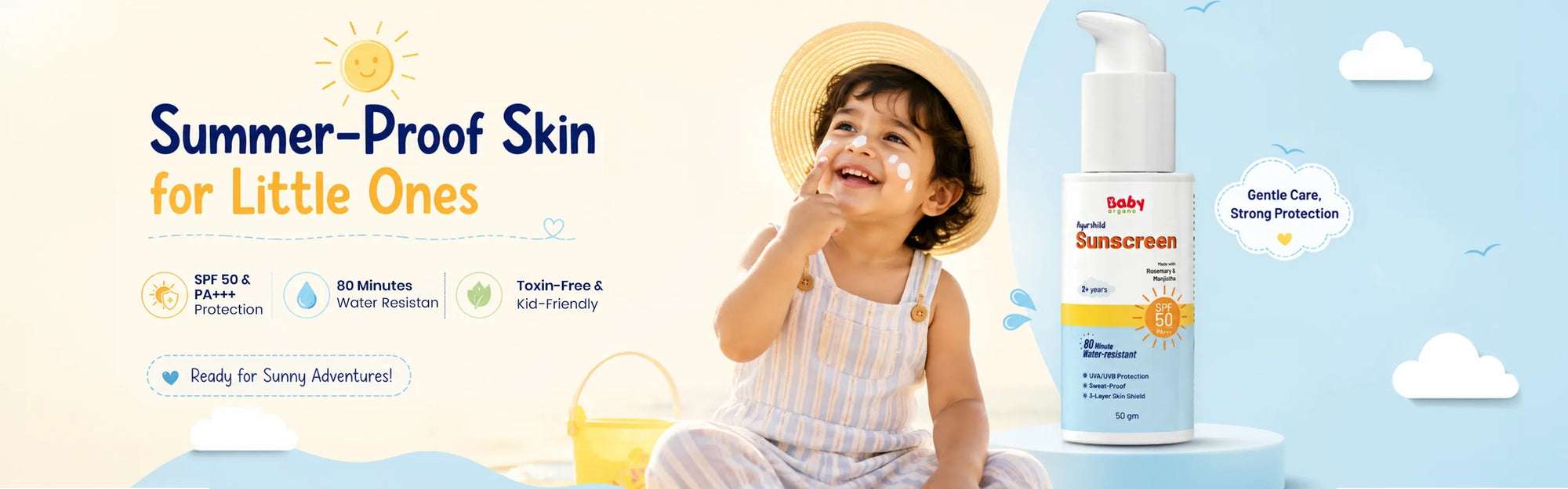 A happy toddler wearing a straw hat with sunscreen on their cheeks, sitting on a beach next to a bottle of BabyOrgano Ayurshild Sunscreen SPF 50, featuring 80 minutes of water resistance and toxin-free protection for kids.