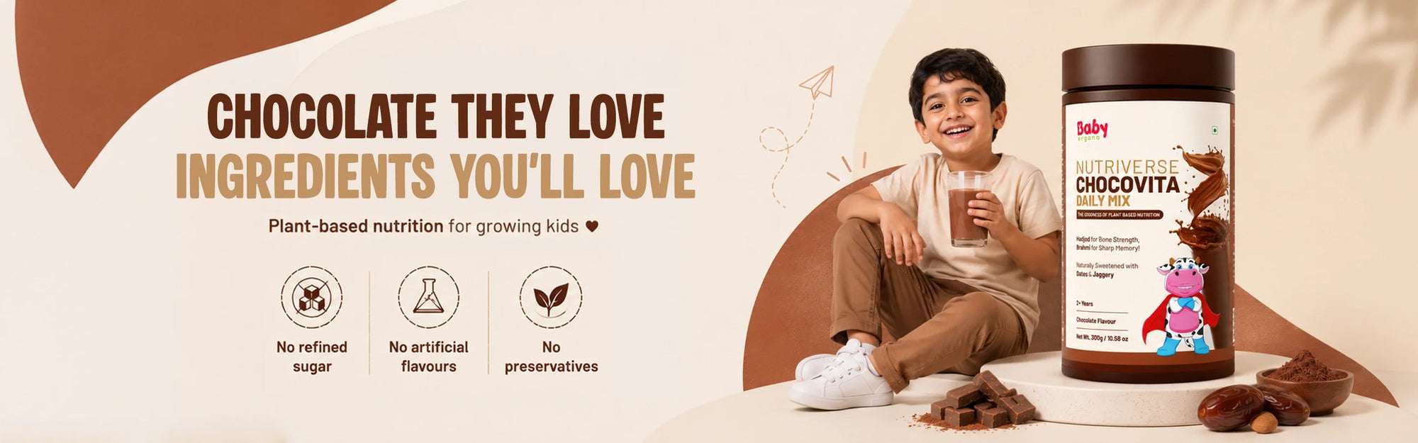 A smiling young boy holding a glass of chocolate milk next to a jar of BabyOrgano Chocovita Nutriverse Daily Mix, highlighting plant-based nutrition for kids with no refined sugar, artificial flavors, or preservatives.