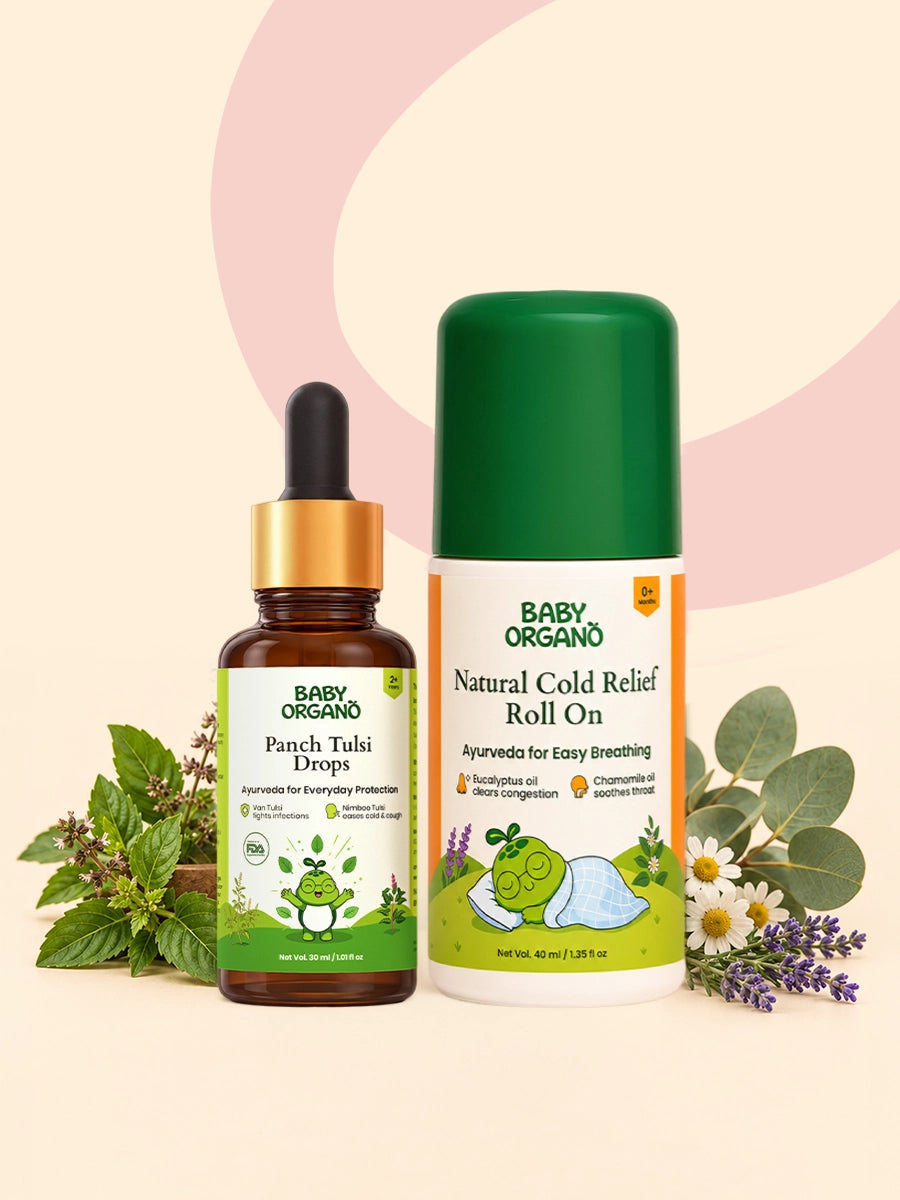 A bottle of BabyOrgano Panch Tulsi Drops sitting alongside a BabyOrgano Natural Cold Relief Roll On bottle against a soft pink background with fresh holy basil, chamomile, and lavender flowers.