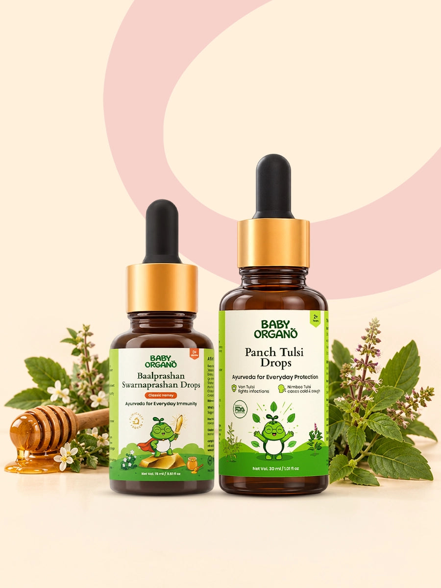 BabyOrgano Baalprashan Swarnaprashan Drops and Panch Tulsi Drops displayed alongside fresh tulsi leaves and a honey dipper.